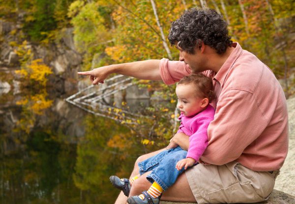 A man a baby sitting next to a lake
